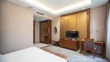 A hotel room with a bed, a desk, a television, and a wardrobe.
