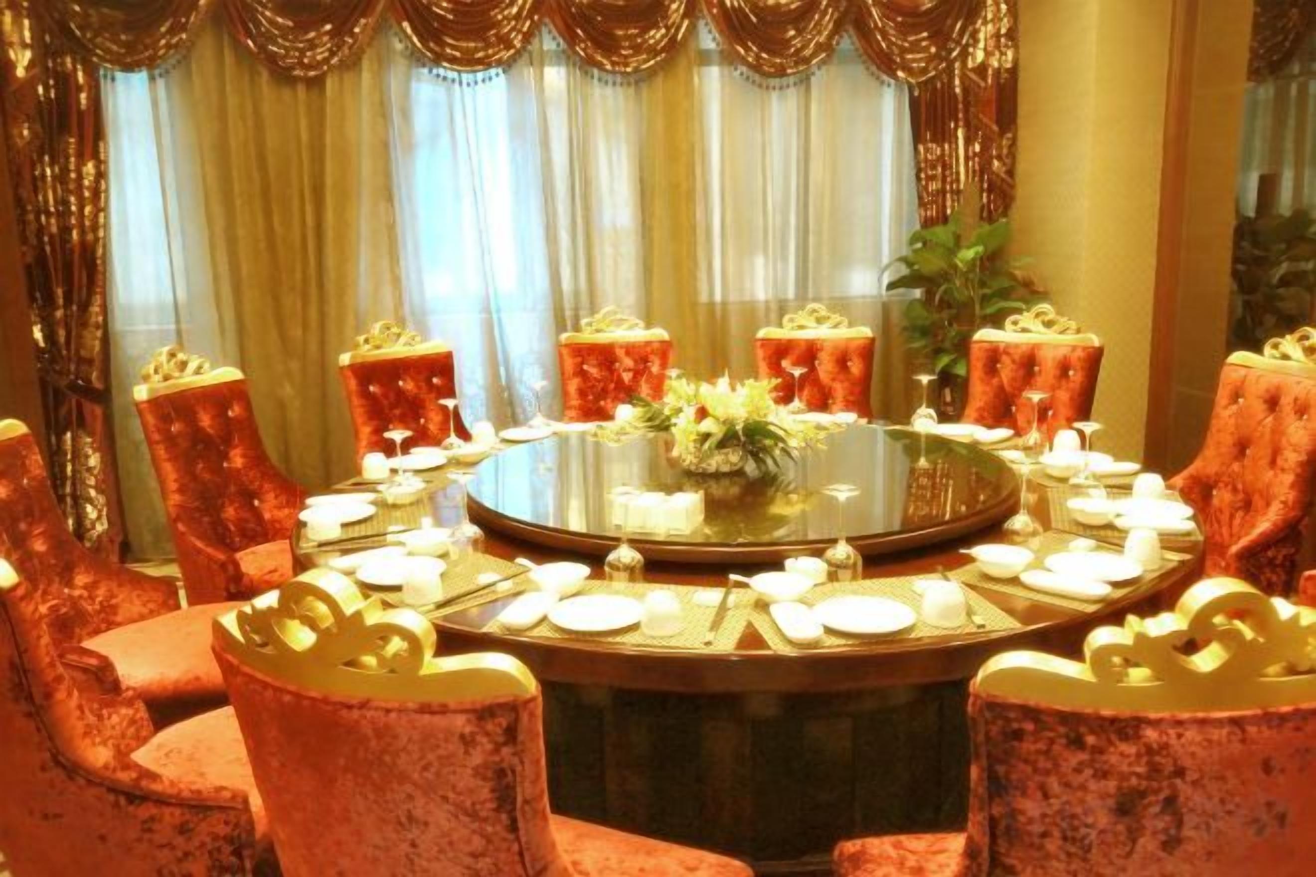 Une table ronde entourée de chaises, un arrangement floral au centre et des bougies.