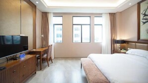 Een hotelkamer met een bed, een bureau met een televisie, een stoel en een raam.
