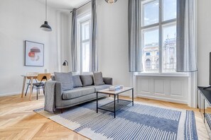 Relax in this stylish space with a sofa, coffee table, and dining area, offering a view of a historic building.