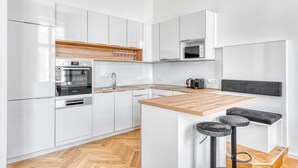 Una cocina moderna con armarios blancos, encimera de madera y microondas integrado.