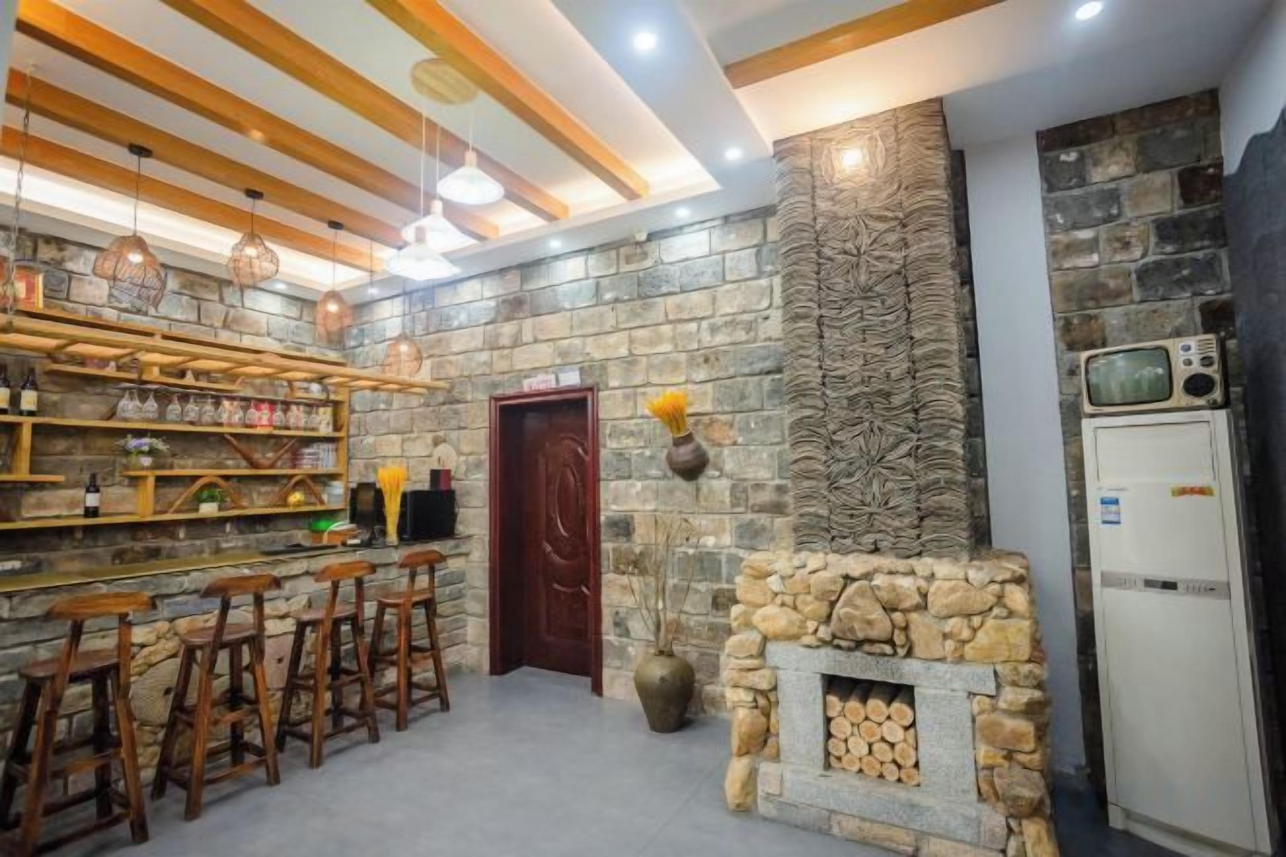 Un rincón bar con taburetes de madera, una chimenea de piedra y un televisor.
