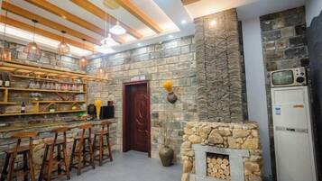 Un rincón bar con taburetes de madera, una chimenea de piedra y un televisor.