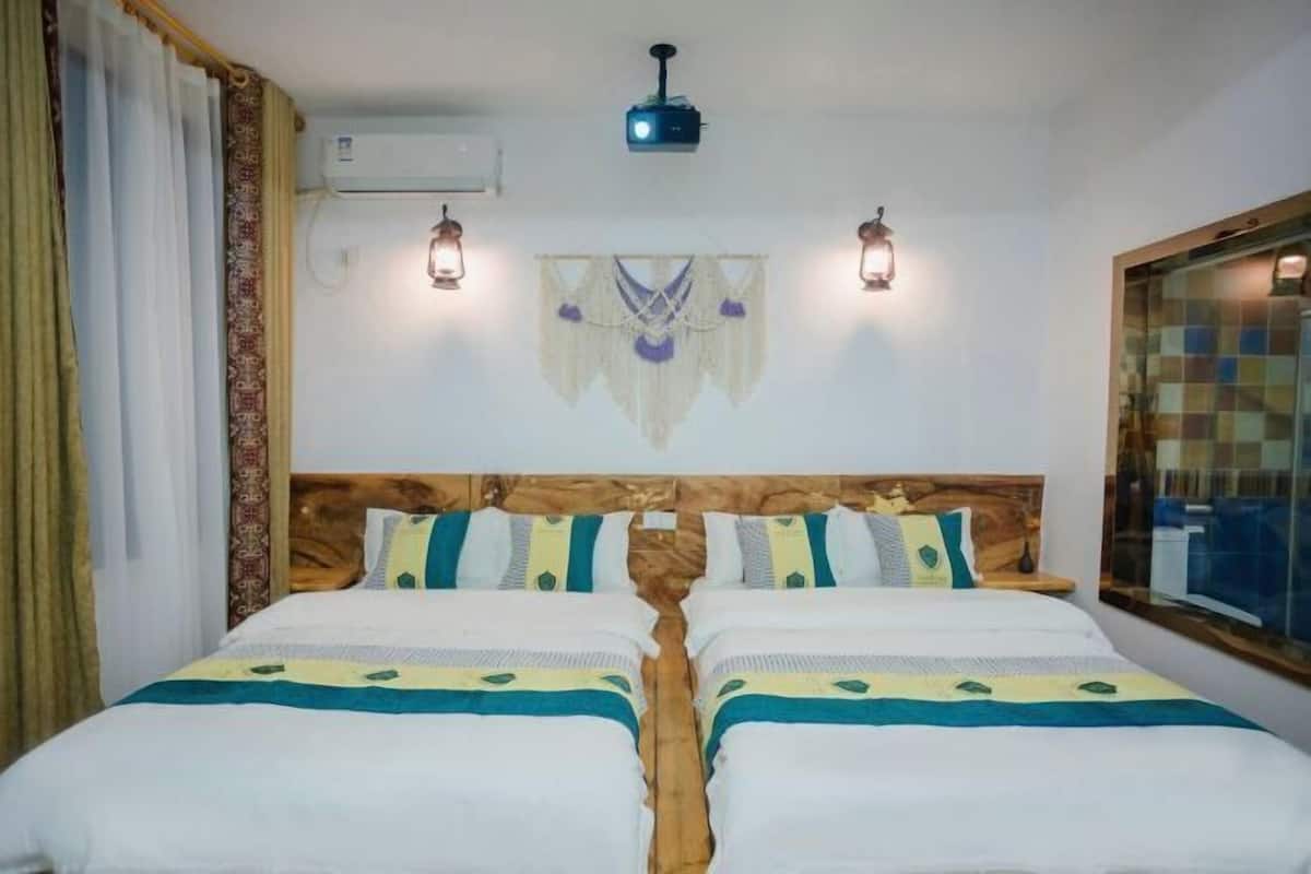 A double bed with a wooden headboard, two bedside lamps, and a wall-mounted air conditioner.