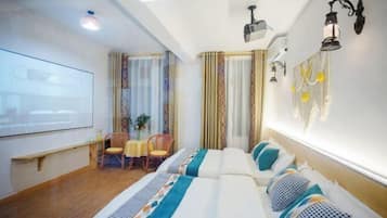 Habitación de hotel con cama, escritorio, silla, pantalla de proyector y ventana con cortinas.