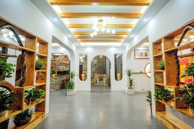 A spacious lobby with wooden shelving units, a stone fireplace, and a modern ceiling design.