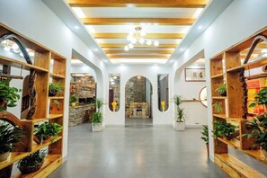 A spacious lobby with wooden shelving units, a stone fireplace, and a modern ceiling design. - Chanji Shanshecinema Theme Inn (Hengyang)
