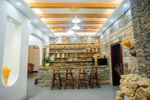 A bar area with stools, a stone wall, and hanging lights. - Chanji Shanshecinema Theme Inn (Hengyang)