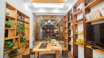 A cozy room with wooden bookshelves, a central table, and a television.