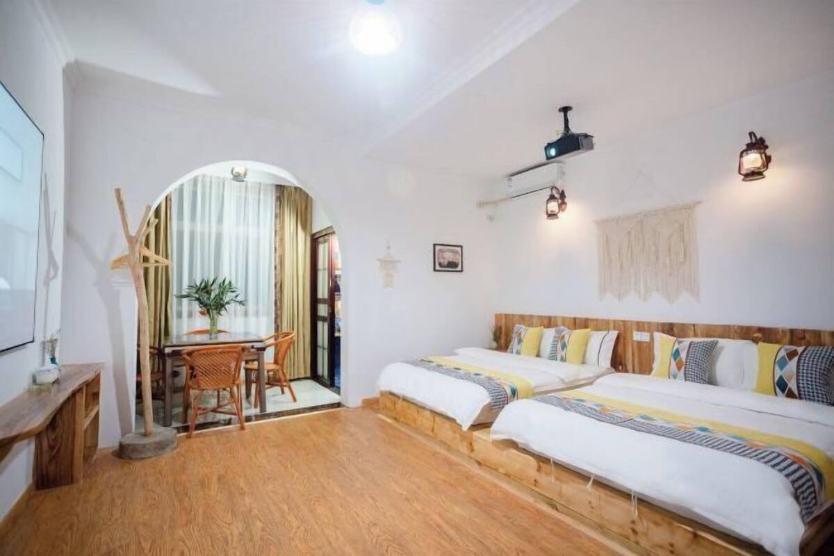 A room with two beds, a dining area, and a small table with chairs.