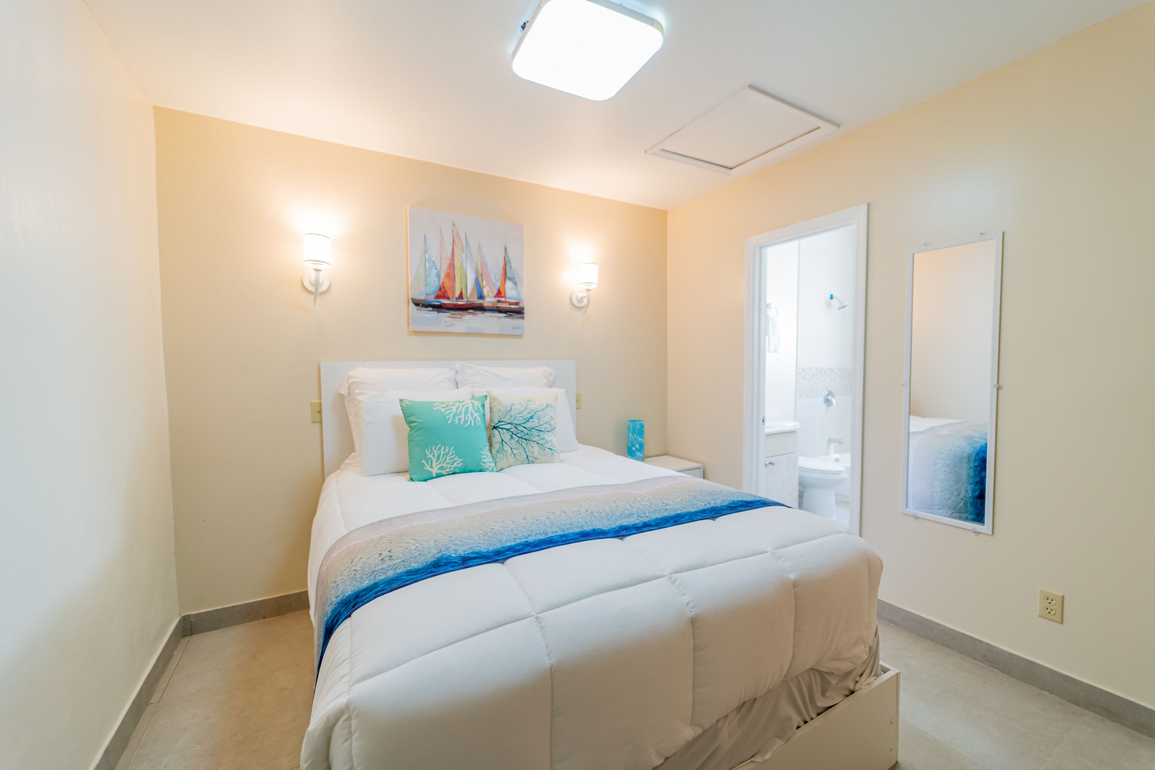 Una camera da letto con un letto, comodini, un quadro e una porta che conduce al bagno.