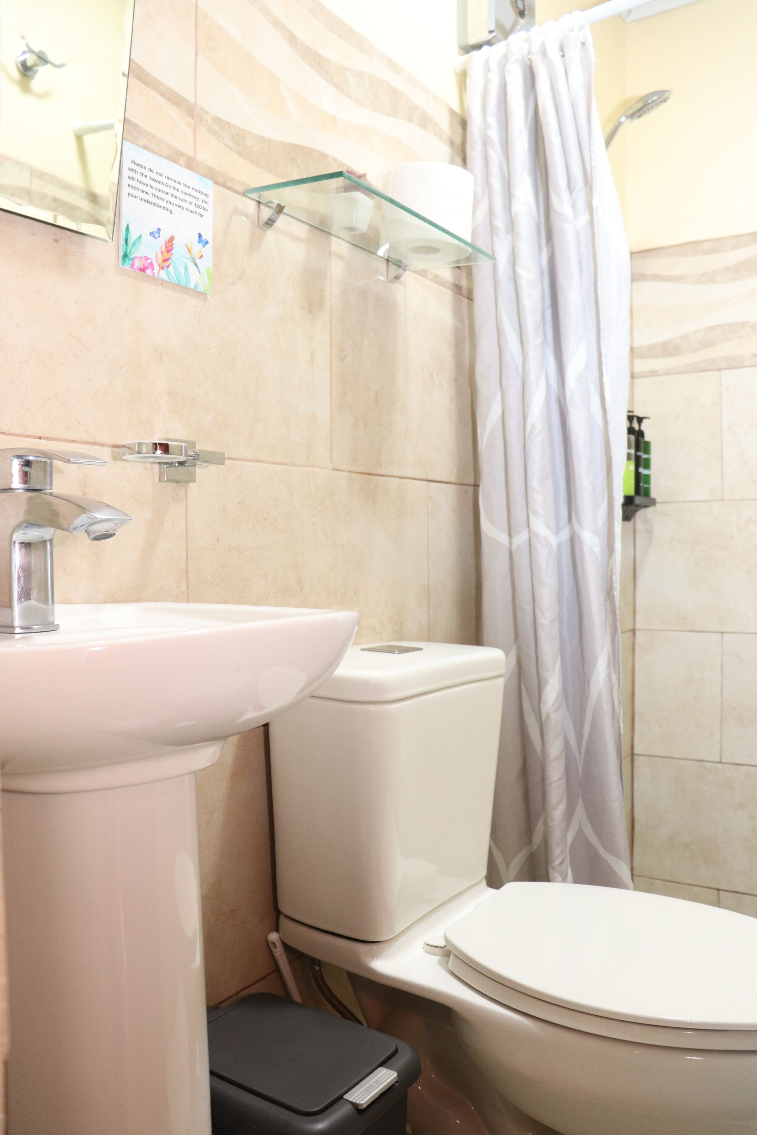 Un bagno con lavandino, wc e tenda da doccia bianchi.