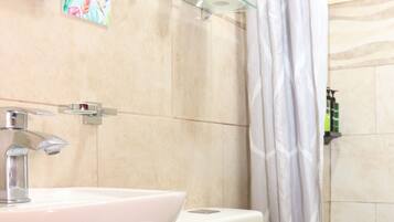 Un bagno con lavandino, wc e tenda da doccia bianchi.