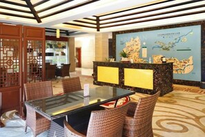 A reception area with a reception desk, seating area, and a large map on the wall. - Longhushan Daoyuan Villa (Guixi)