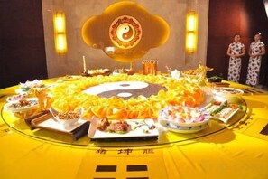 A round table with various dishes and a central emblem, surrounded by a yellow tablecloth with Chinese characters. - Longhushan Daoyuan Villa (Guixi)