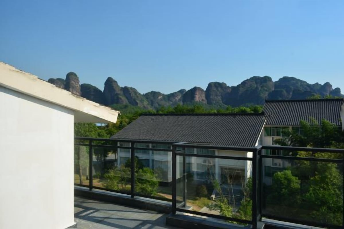 Een modern gebouw met een glazen balkon met uitzicht op een bergachtig landschap.