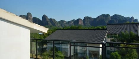 Un edificio moderno con balcón de vidrio que ofrece vistas a un paisaje montañoso.
