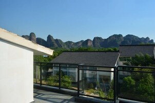 Un edificio moderno con balcón de vidrio que ofrece vistas a un paisaje montañoso.