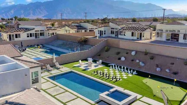 A pool area with multiple pools, lounge chairs, and a view of mountains. - Summer specials! Pool+spa+gameroom+putting green (Desert Hot Springs)