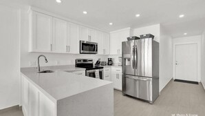 A modern kitchen with white cabinetry, stainless steel appliances, and a central island. - Spectacular Ocean View Condo in Beachfront Resort (South Padre Island)