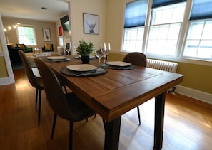 A dining area with a wooden table set for four, chairs, and a potted plant. - Lofty Elegant Home In Downtown Princeton (Princeton)