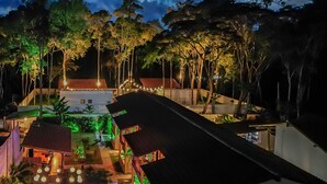A resort with a swimming pool, multiple buildings, and a well-lit garden area.