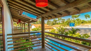 A wooden deck with a pool, surrounded by palm trees and a clear view of the pool area.