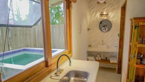 A bathroom with a window, a sink, and a wooden cabinet.