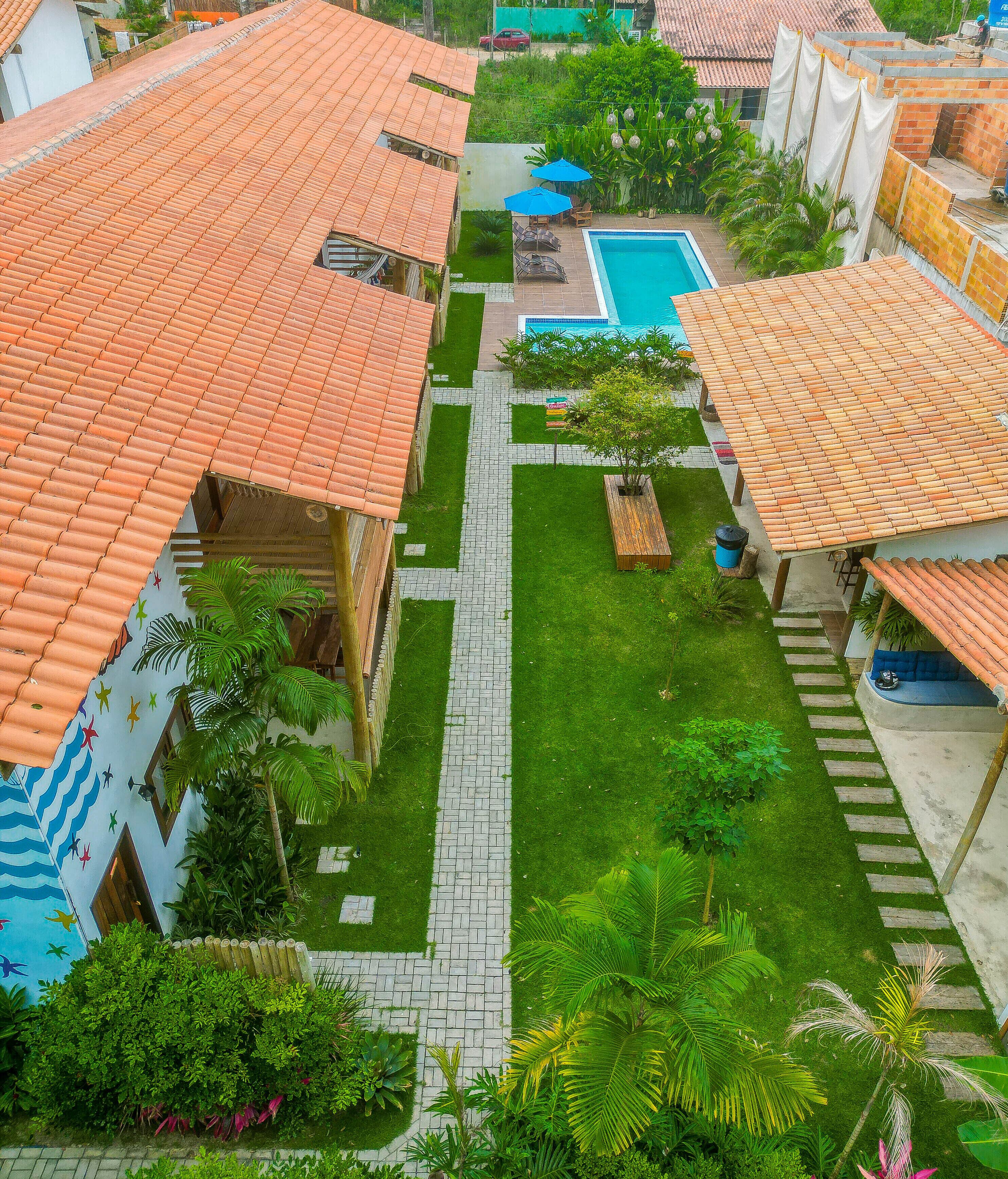 Um pátio com piscina, telhados em cerâmica e um caminho central.