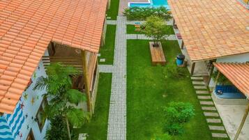 Um pátio com piscina, telhados em cerâmica e um caminho central.