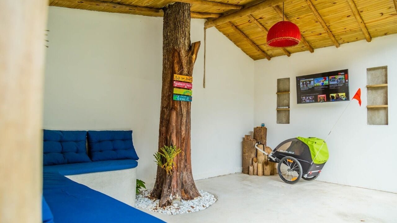 A room with a blue sofa, a tree trunk with colorful signs, a baby stroller, and a red hanging light.