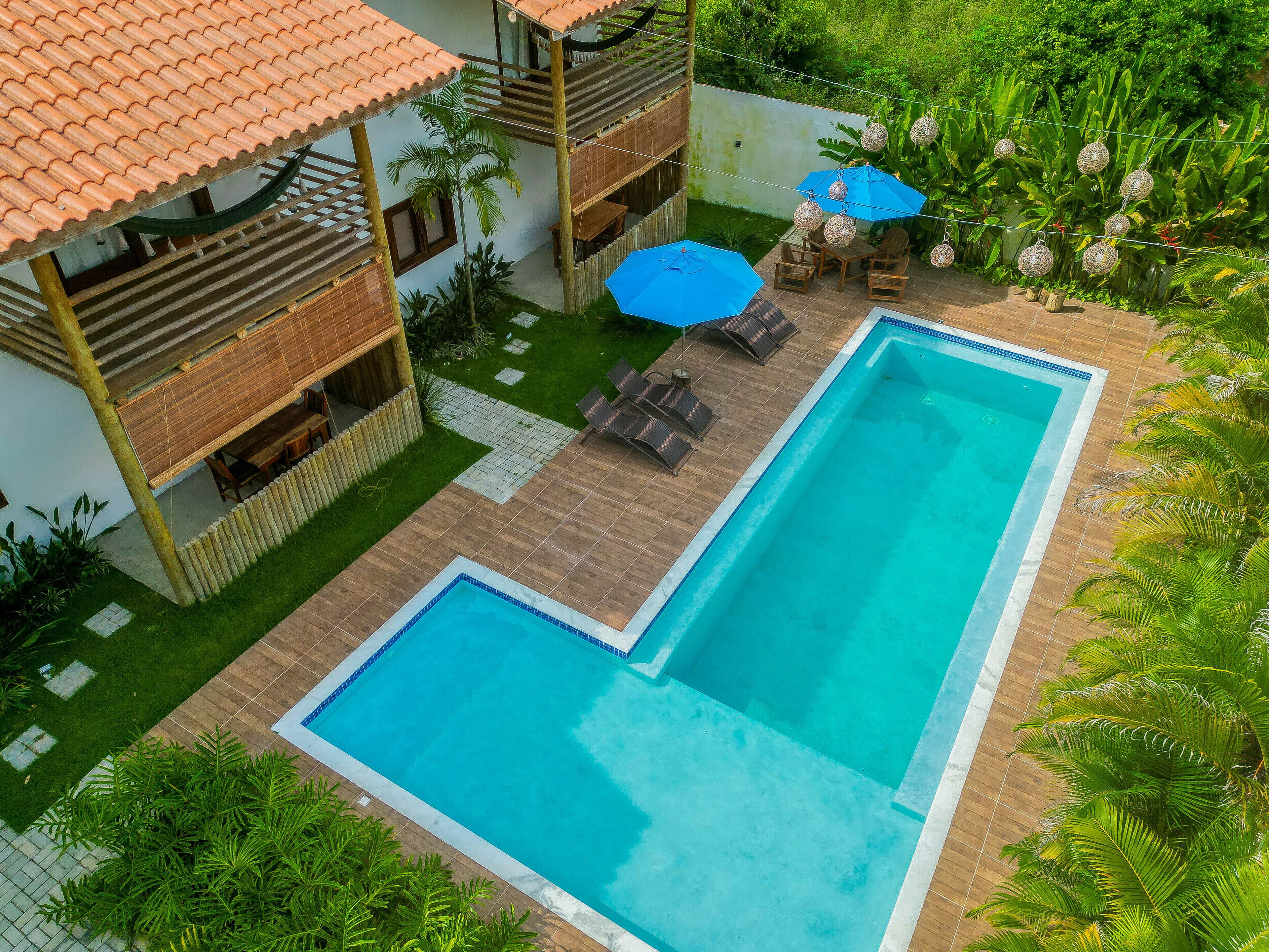Ein rechteckiger Pool mit Holzterrasse und blauem Sonnenschirm.