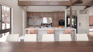 Cozinha moderna com armários de madeira, uma ilha central com banquetas e vista para o exterior.
