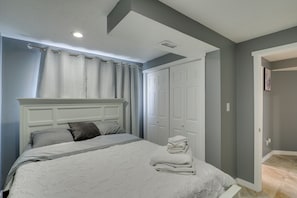 Une chambre à coucher comprenant un lit, une tête de lit, une armoire et une porte donnant sur une autre pièce.