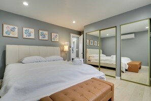Une chambre moderne avec un grand lit, un miroir et des œuvres d’art accrochées au mur.
