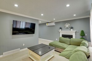 Un salon équipé d’un téléviseur à écran plat, d’un canapé, d’une table basse, d’une cheminée et de spots encastrés dans le plafond.