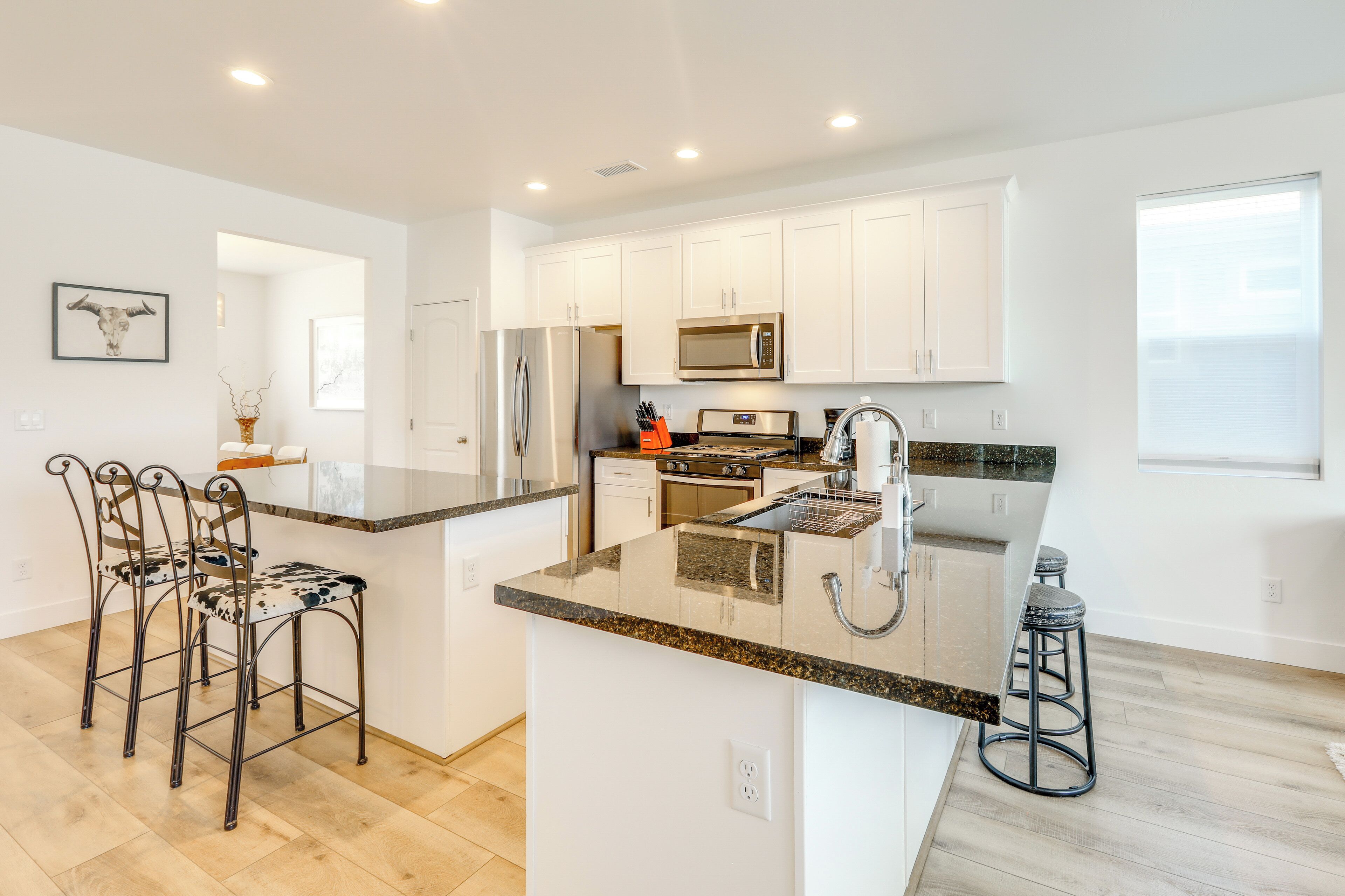 A modern kitchen with white cabinets, stainless steel appliances, and a granite countertop.