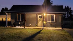 Una casa de una sola planta con un porche cubierto, una puerta principal y una pequeña mesa y sillas afuera.
