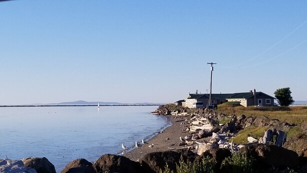 Escena costera con un litoral rocoso, una casa y cielo despejado.