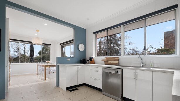 A modern kitchen with white cabinets, a dishwasher, and a large window. - Uralla | Lovely house with pool (West Bathurst)