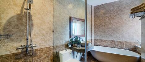 A modern bathroom with a freestanding bathtub, a showerhead, and a toilet.