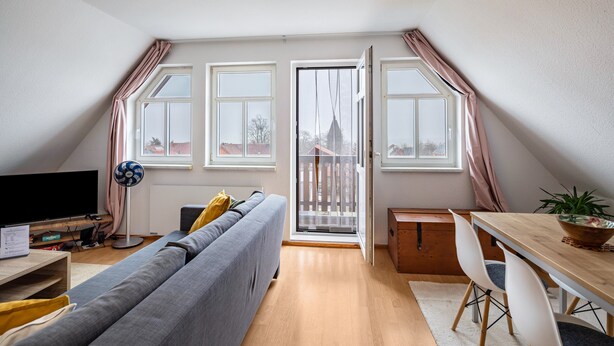 Una sala moderna con sofá, televisor y comedor con sillas y una mesa.