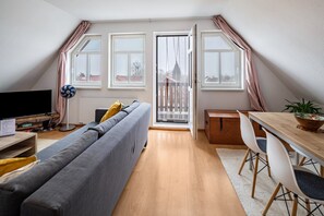A modern living room with a sofa, TV, and dining area with chairs and a table. - Apartment "am Hainich" with Private Balcony & Wi-Fi (Craula)