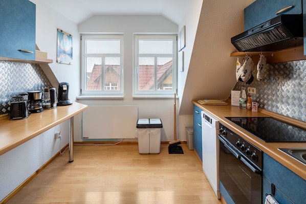 A modern kitchen with a wooden countertop, a built-in oven, and a window overlooking a cityscape. - Apartment "am Hainich" with Private Balcony & Wi-Fi (Craula)