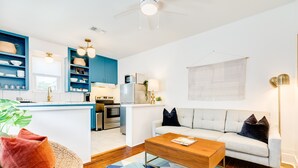 A modern kitchen with blue cabinets, a white island, and a dining area with a sofa and coffee table. - Modern dog-friendly duplex, 1 block from beach with shared backyard patio & W/D (Galveston)