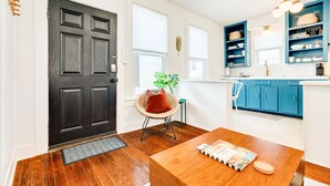 A modern kitchen with blue cabinets, a wooden dining table, and a black door. - Modern dog-friendly duplex, 1 block from beach with shared backyard patio & W/D (Galveston)