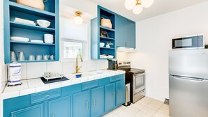 A modern kitchen with blue cabinets, stainless steel appliances, and a white countertop. - Modern dog-friendly duplex, 1 block from beach with shared backyard patio & W/D (Galveston)