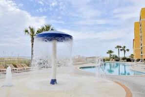 Relax by the resort pool surrounded by palm trees and lounge chairs.