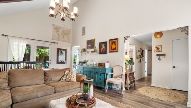 Un salón amplio con un sofá grande color marrón, una mesa de centro de madera con una bandeja, un aparador color turquesa y una puerta blanca al fondo.