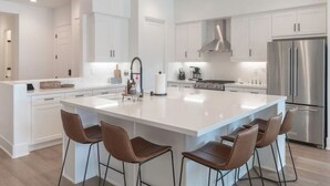 A modern kitchen with a large island, stainless steel appliances, and white cabinetry. - Pool, fire pit & hot tub in La Quinta (La Quinta)